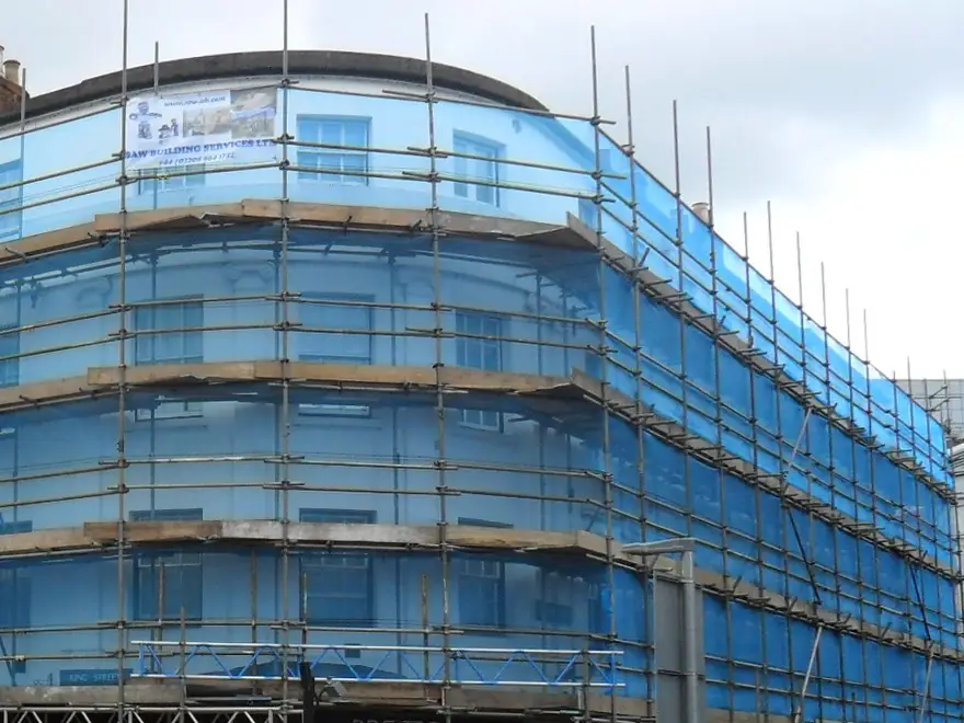 Blue-netted scaffold lifts following the curved corner of The George Hotel, Reading