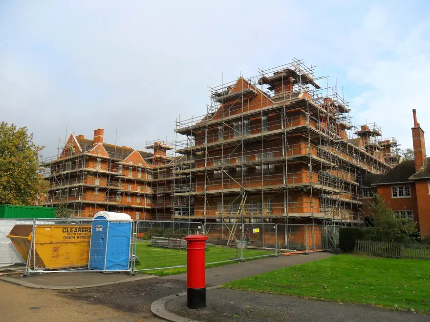 Independent scaffold on red-brick Oxford college buildings beside a lawn
